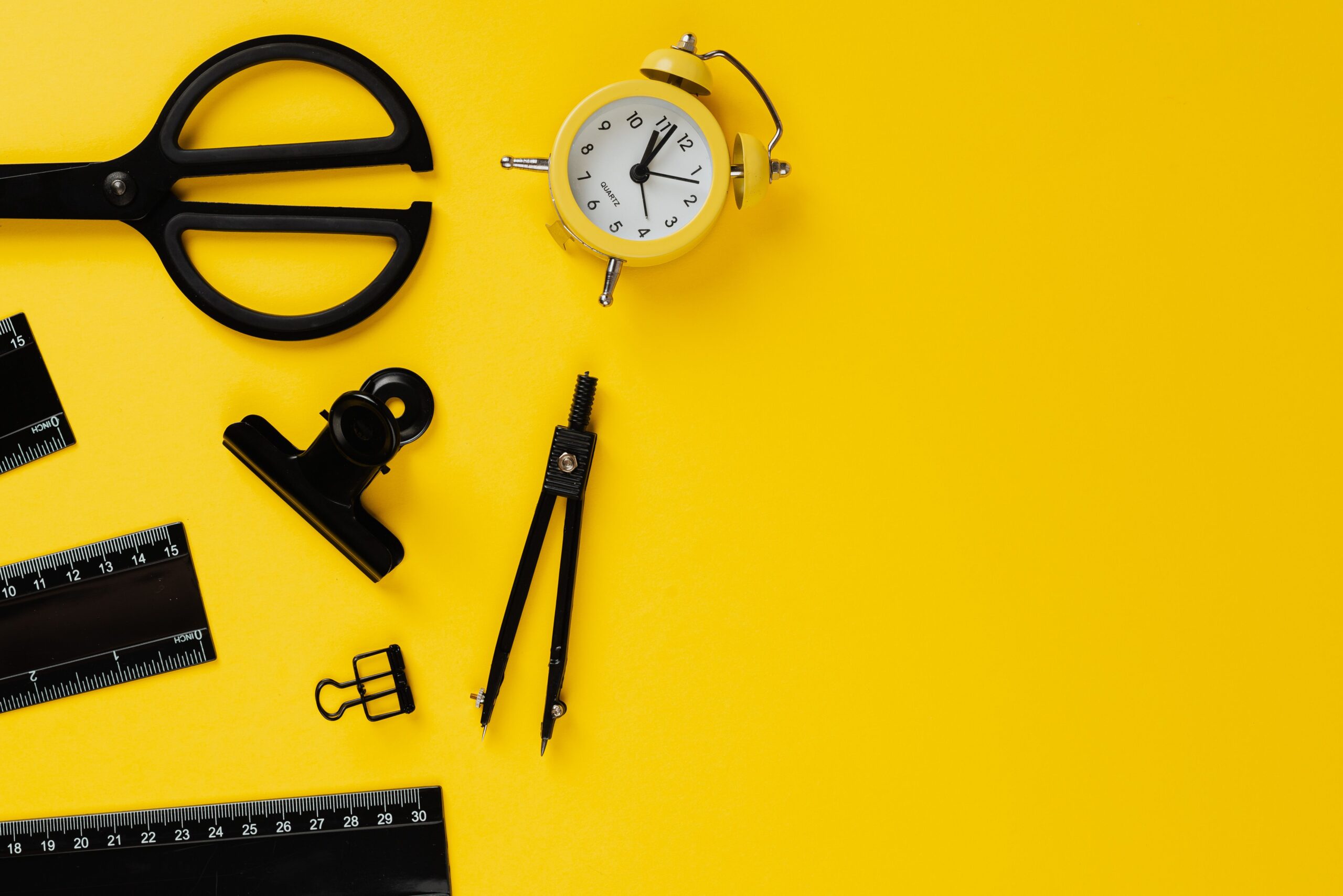 Desk essentials arranged on a vibrant yellow background, perfect for educational and organizational themes.