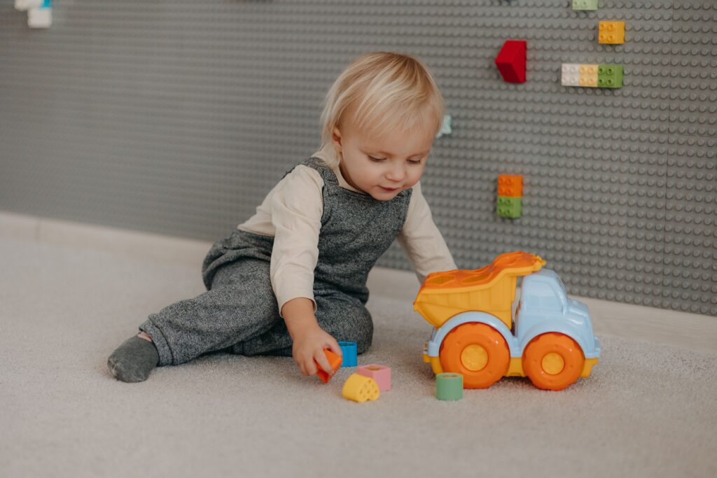 Cute toddler engaged with colorful blocks and toy truck indoors.